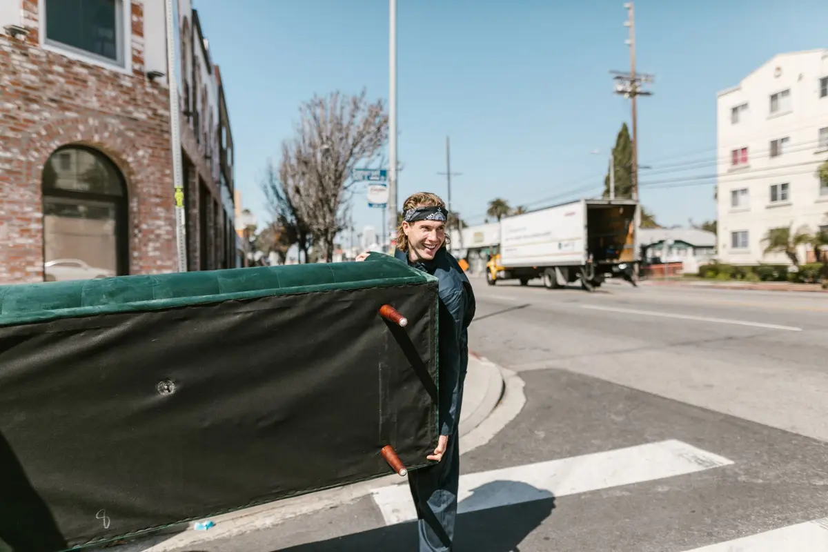 a worker carrying an old chair out to a truck